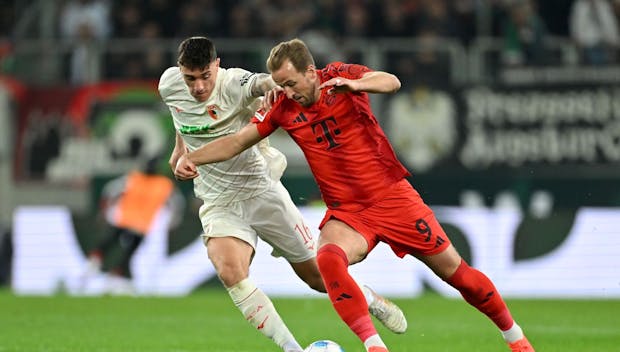 AUGSBURG, GERMANY - APRIL 04: Cedric Zesiger of FC Augsburg battles for possession with Harry Kane of Bayern Munich during the Bundesliga match between FC Augsburg and FC Bayern München at WWK-Arena on April 04, 2025 in Augsburg, Germany. (Photo by Sebastian Widmann/Getty Images)